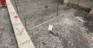 Préparation d’une fondation de gravier nivelée avec règles et piquets pour l’installation de pavé uni