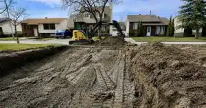 Excavation résidentielle d’un terrain avec une mini-pelle sur un chantier, devant des maisons de quartier.