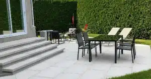Aménagement paysager d’une cour arrière avec terrasse en dalles grises.
